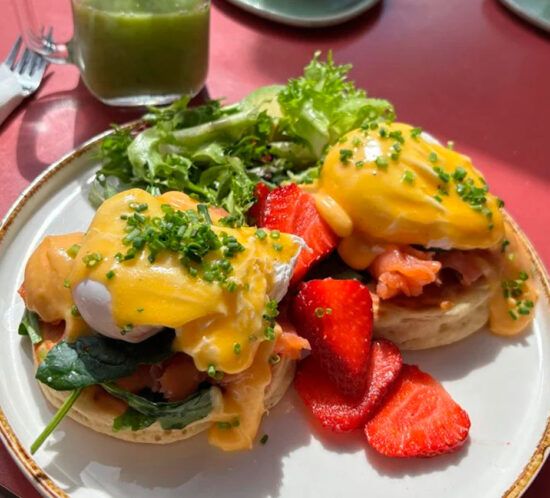 Huevos benedictinos con fresas y ensalada en Elzade Cafe