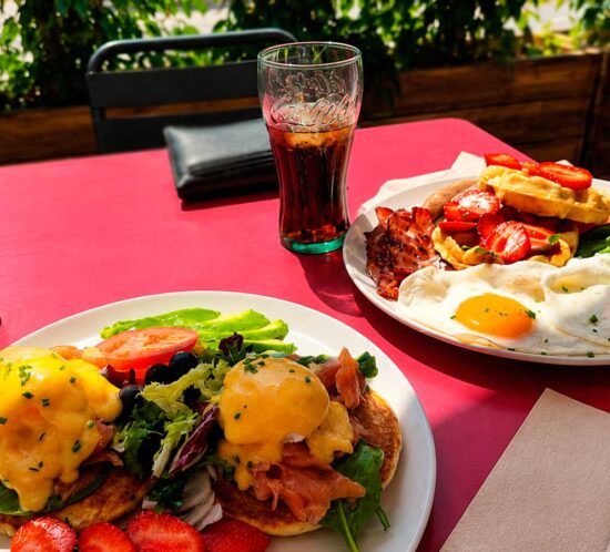 Brunch con huevos fritos, bacon y salchichas en la terraza de Elzade Cafe